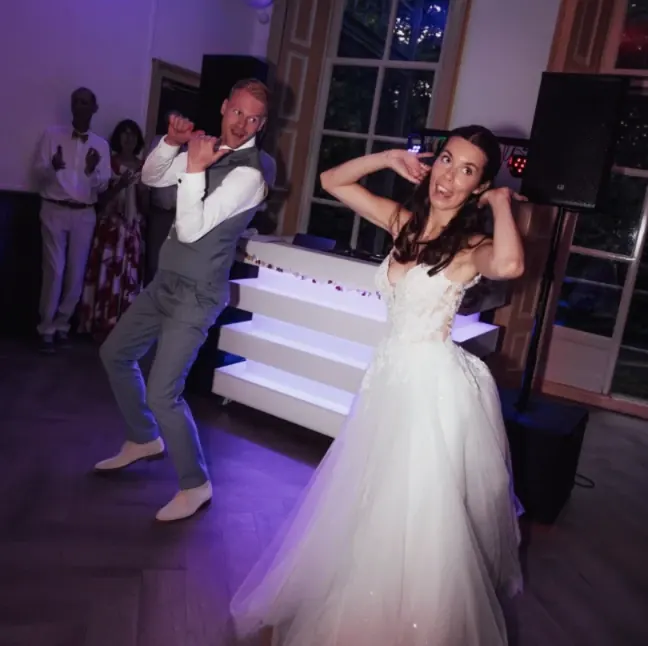 Bruidspaar danst uitgelaten voor de verlichte DJ-booth van BOAZ op hun bruiloft