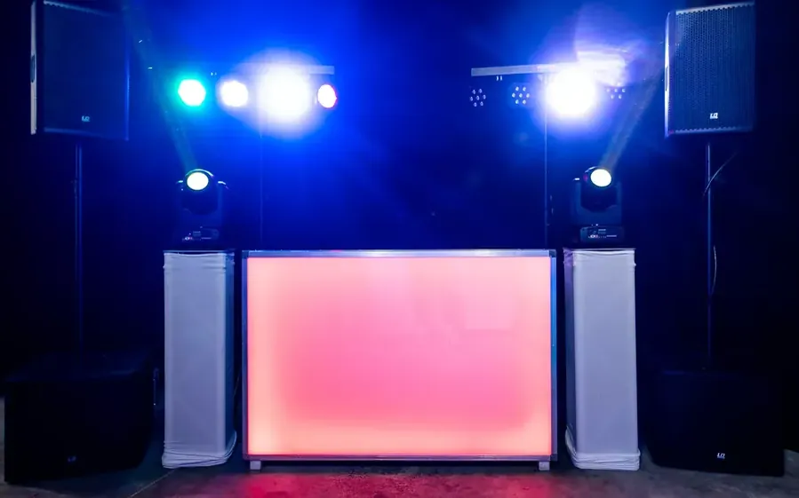 Buurtfeest DJ: verlichte DJ-booth met speakers in de avond