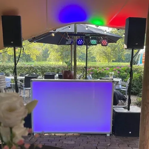 DJ-booth met parasol en verlichting op een bruiloft buiten