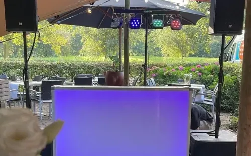 DJ bruiloft Arnhem: DJ-booth onder een parasol op een trouwfeest in de buitenlucht