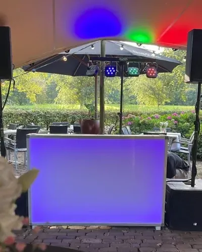 DJ bruiloft Gelderland: DJ-booth onder een parasol op een trouwfeest in de tuin