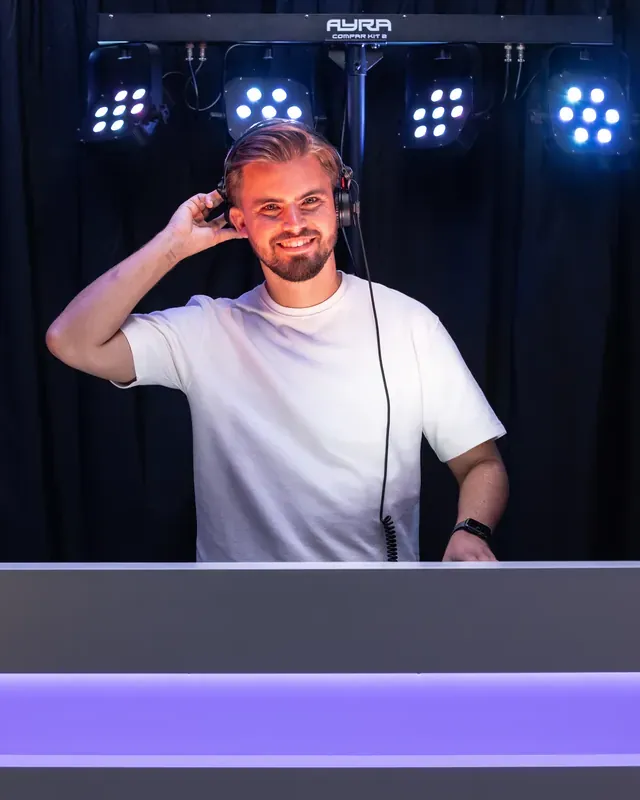 DJ huren: DJ van BOAZ Entertainment met koptelefoon achter een verlichte booth