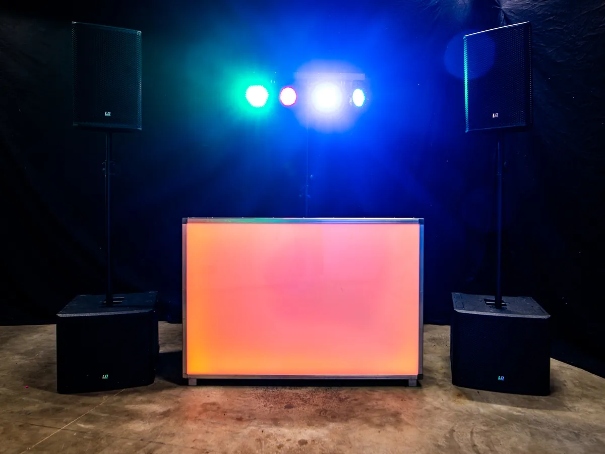 DJ huren Doesburg: oranje verlichte DJ-booth met speakers en lichtshow van BOAZ