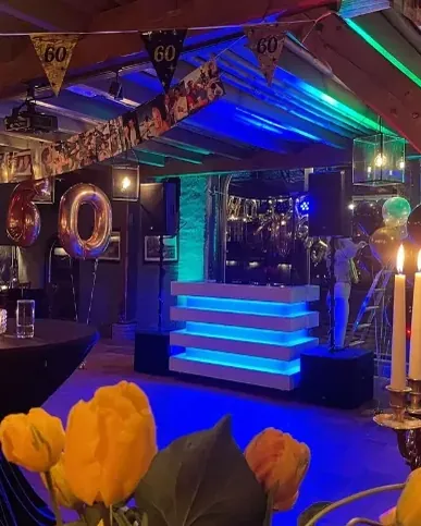 Jubileumfeest organiseren: DJ-booth in een feestzaal met kaarsen en bloemen