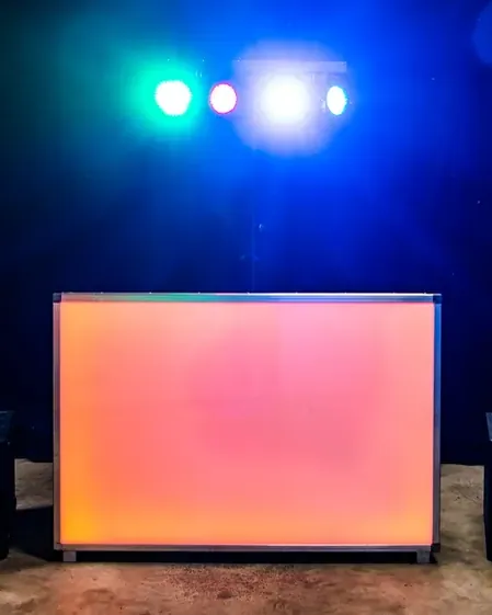 Muziek huren voor feestje: verlichte DJ-booth met speakers op een buitenfeest