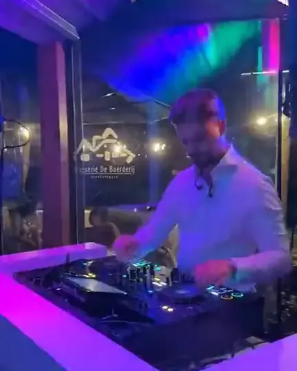 Pioneer DJ set huren: DJ draait achter een verlichte booth met mixer